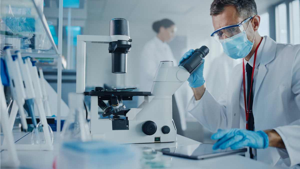 Scientist using microscope and tablet during AI assisted fermentation research in lab